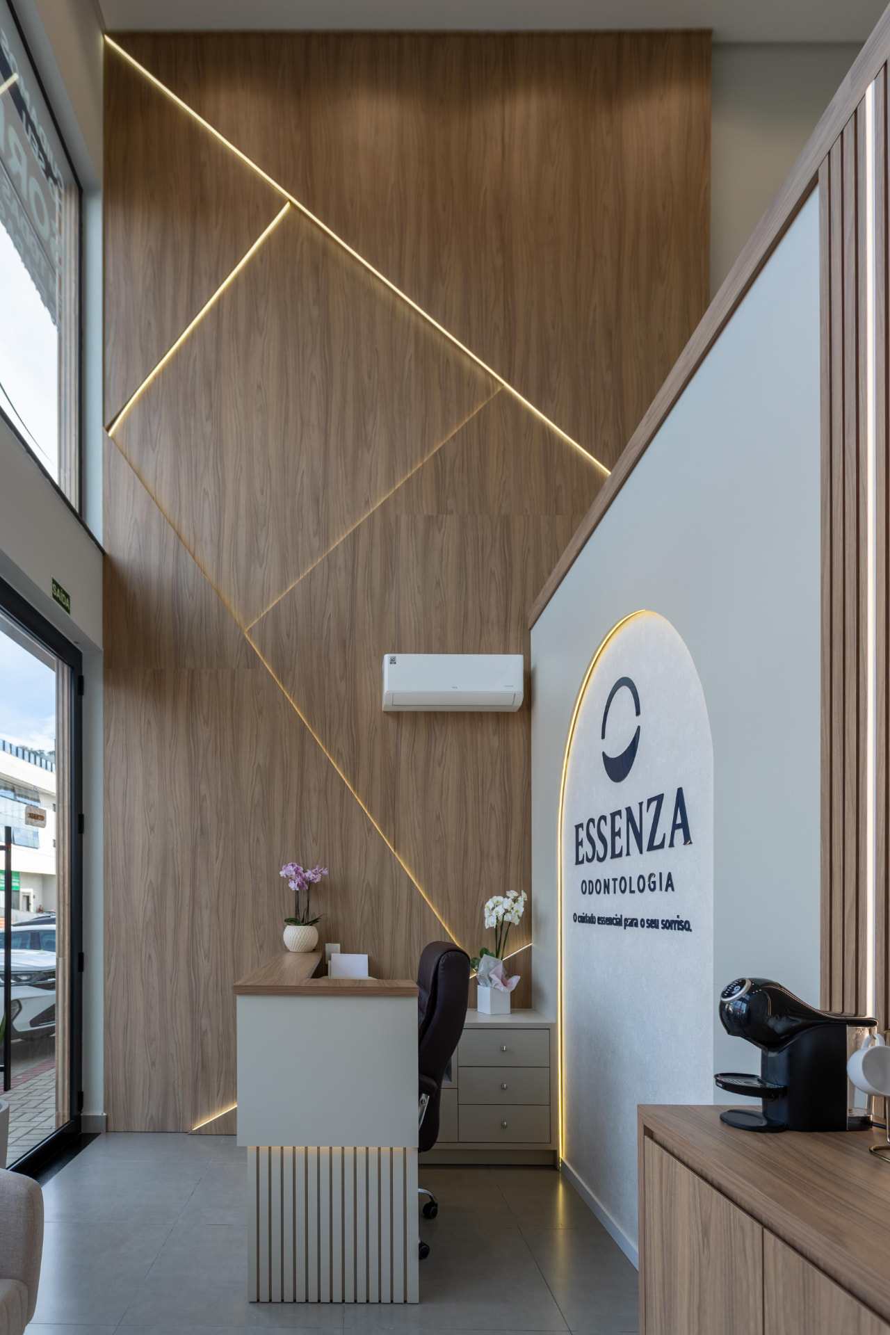 Hall de entrada da Essenza Odontologia com painel de madeira e iluminação linear